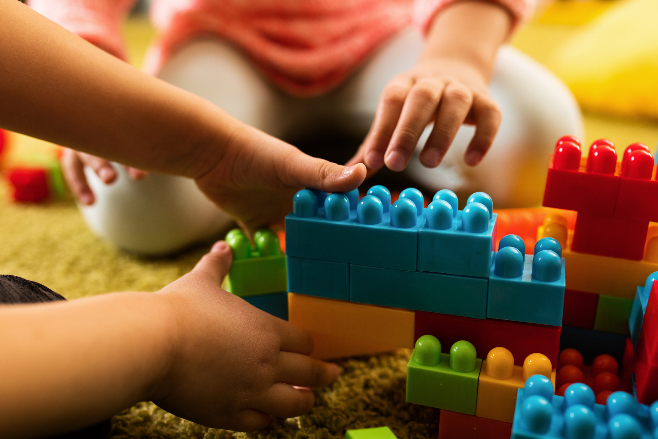 Close-up of two children playing with toy blocks.